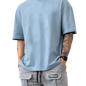 Man wearing light blue oversized t-shirt and gray cargo pants with smartwatch and tattoo on arm.