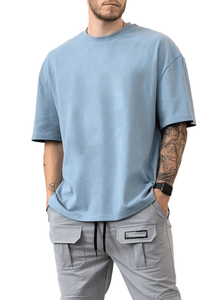 Man wearing light blue oversized t-shirt and gray cargo pants with smartwatch and tattoo on arm.