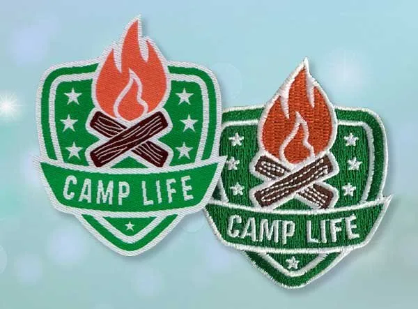 Embroidered Camp Life patch with a green shield design, featuring flames and crossed logs, symbolizing the spirit of camping.