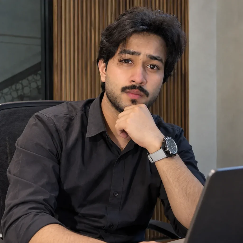 Talha Asif wearing a black shirt and watch sitting at a desk