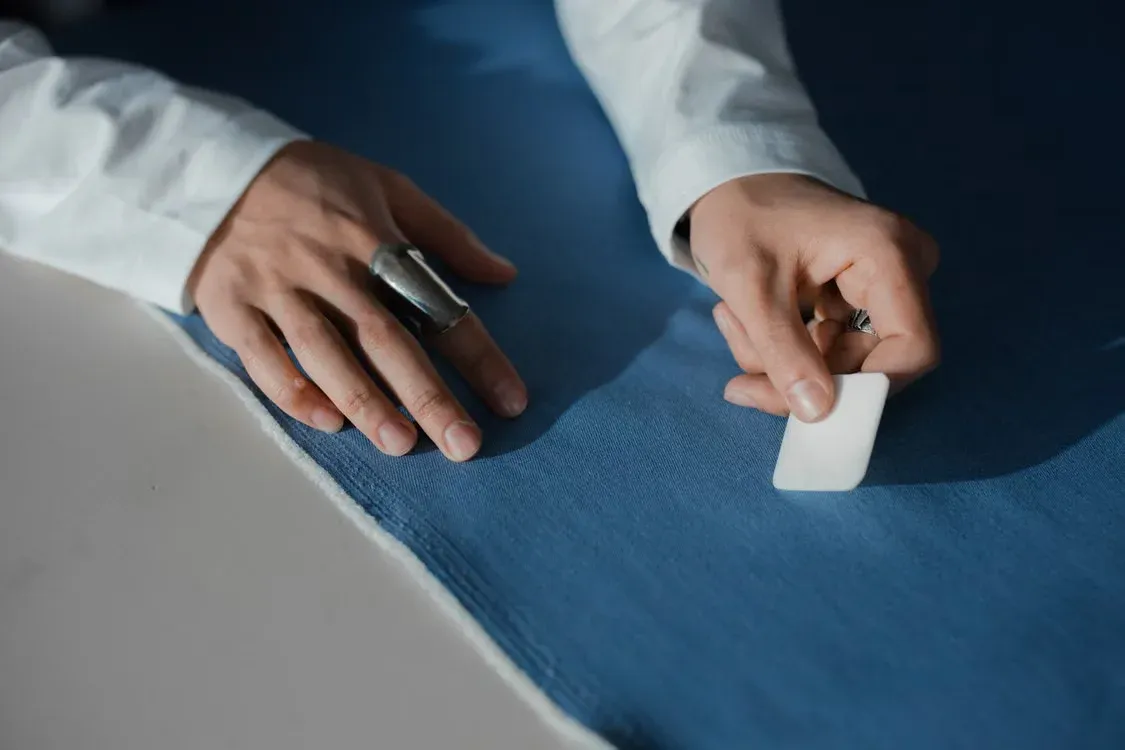 Hands of a designer working with a blue fabric sample for custom clothing